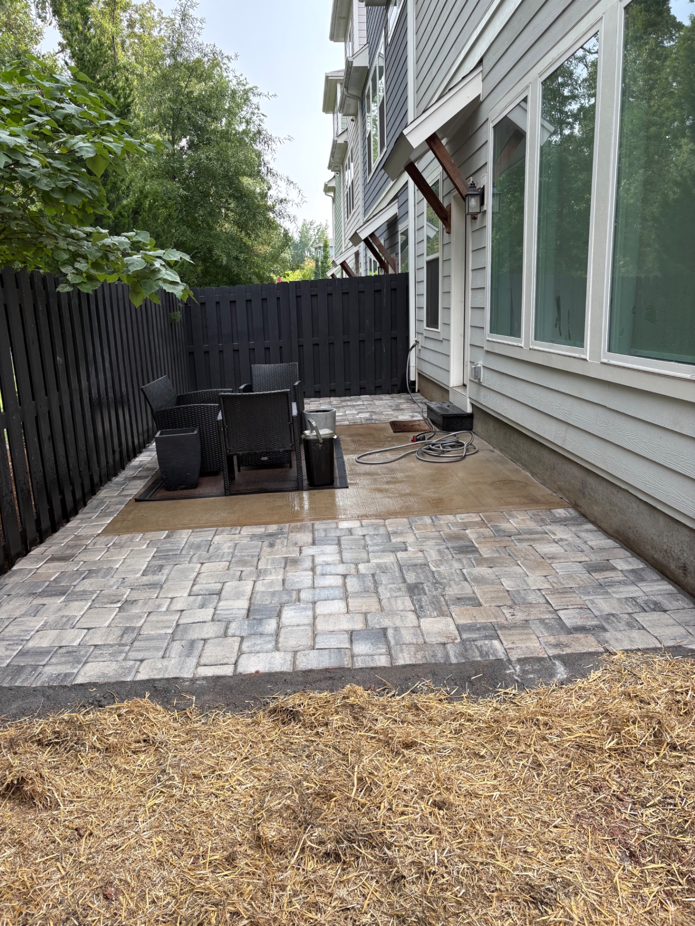 Gray tumbled paver patio beside a townhome enclosed by a dark privacy fence in Mooresville, NC