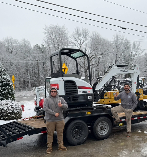 Southern Style Turf & Design crew with a mini excavator on a trailer during a snowy day in the Lake Norman area