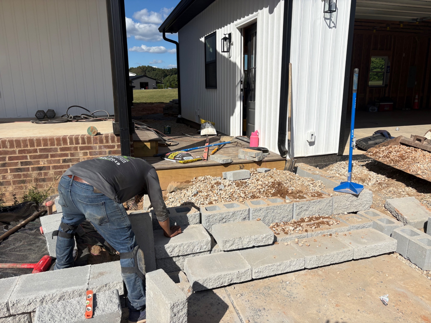 Crew laying block steps beside a new wall and concrete walkway at a residential property