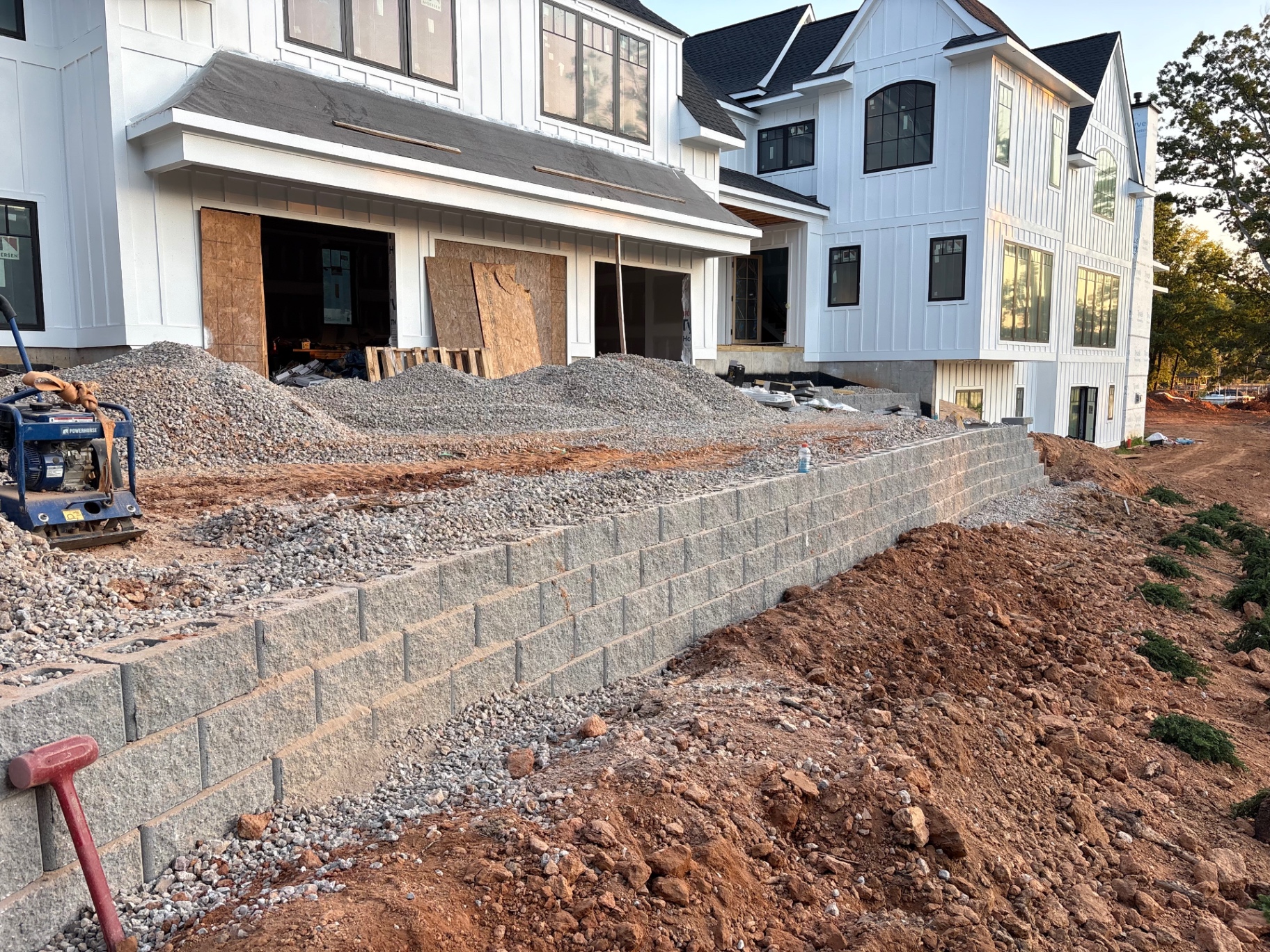Long segmental block retaining wall under construction beside a new Lake Norman area home