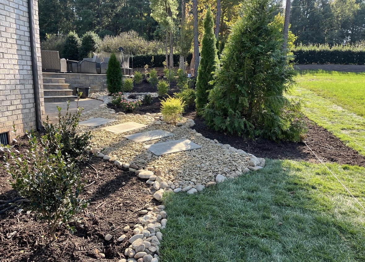 River rock path with flagstone stepping stones between new mulched planting beds and fresh sod in Mooresville, NC